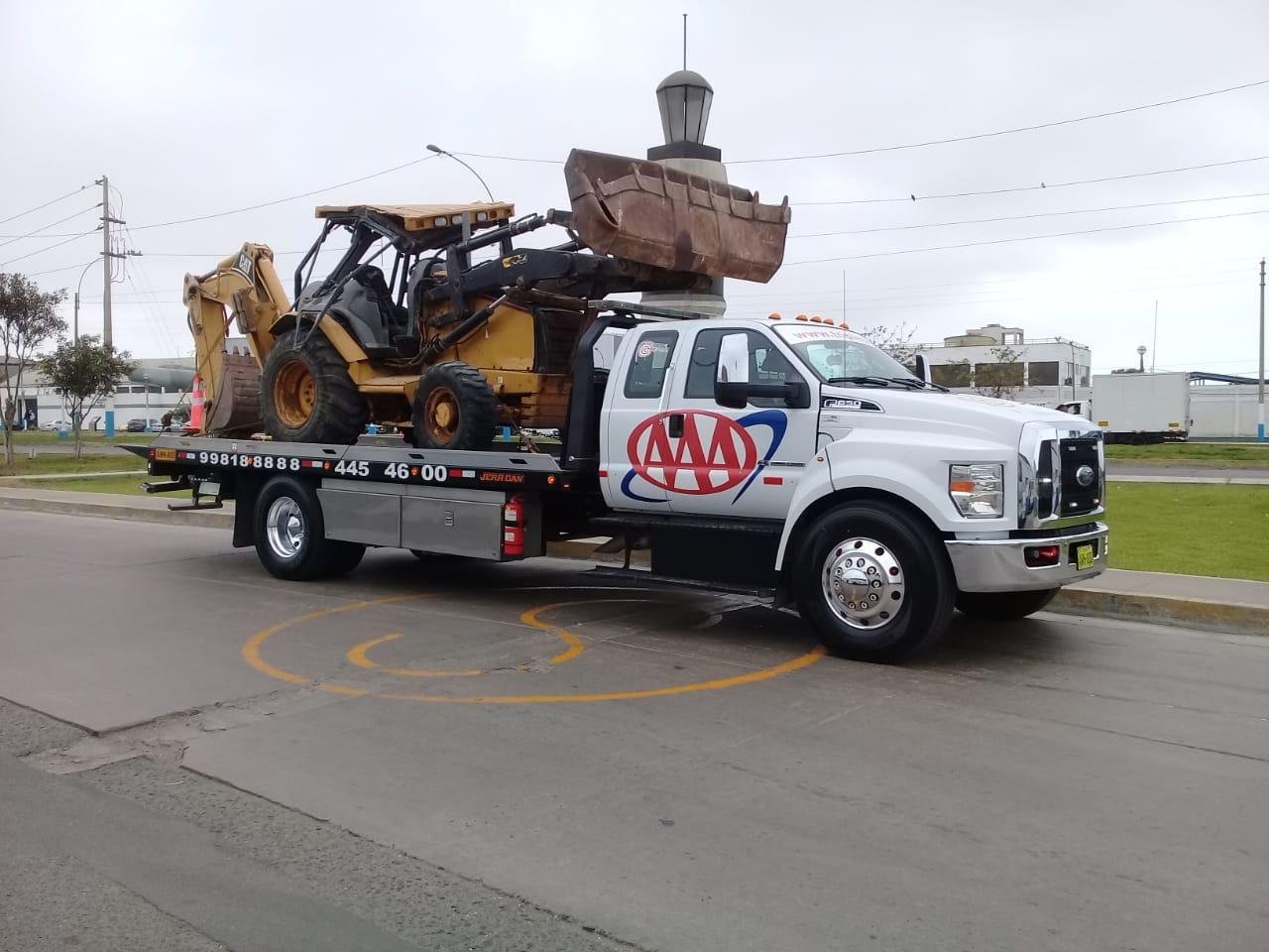 Grúa plataforma trasladando una retroexcavadora Caterpillar