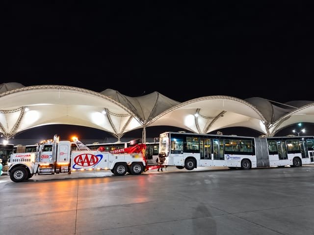 Grúa de Grúas Triple A con un bus articulado de noche