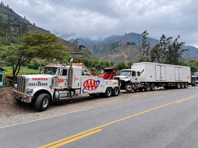 Grúa pesada remolcando un camión por una carretera entre cerros