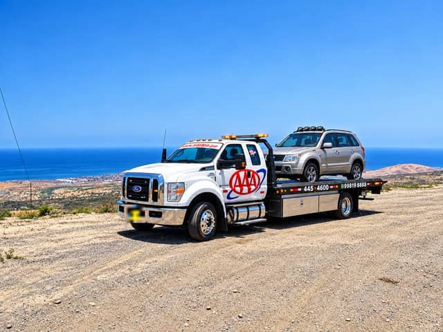 Grúa plataforma Ford F-650 de Grúas Triple A trasladando una camioneta