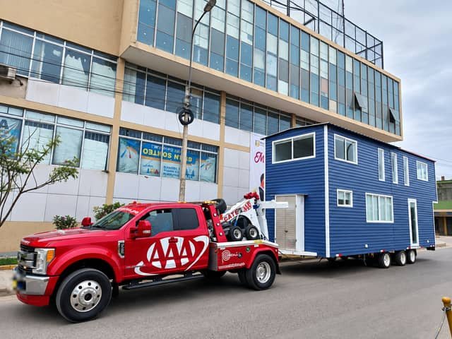Grúa de arrastre Ford F-450 de Grúas Triple A remolcando una casa prefabricada por la ciudad