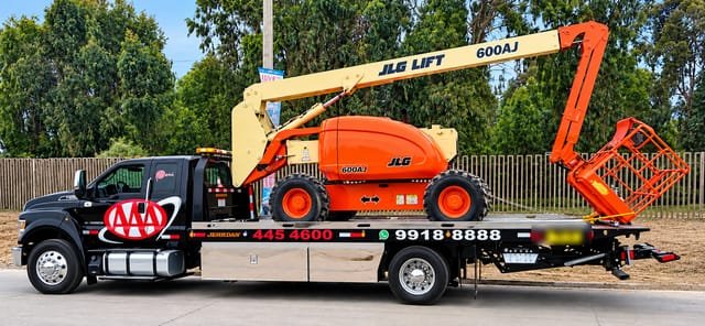 Elevador articulado JLG naranja trasladado en plataforma